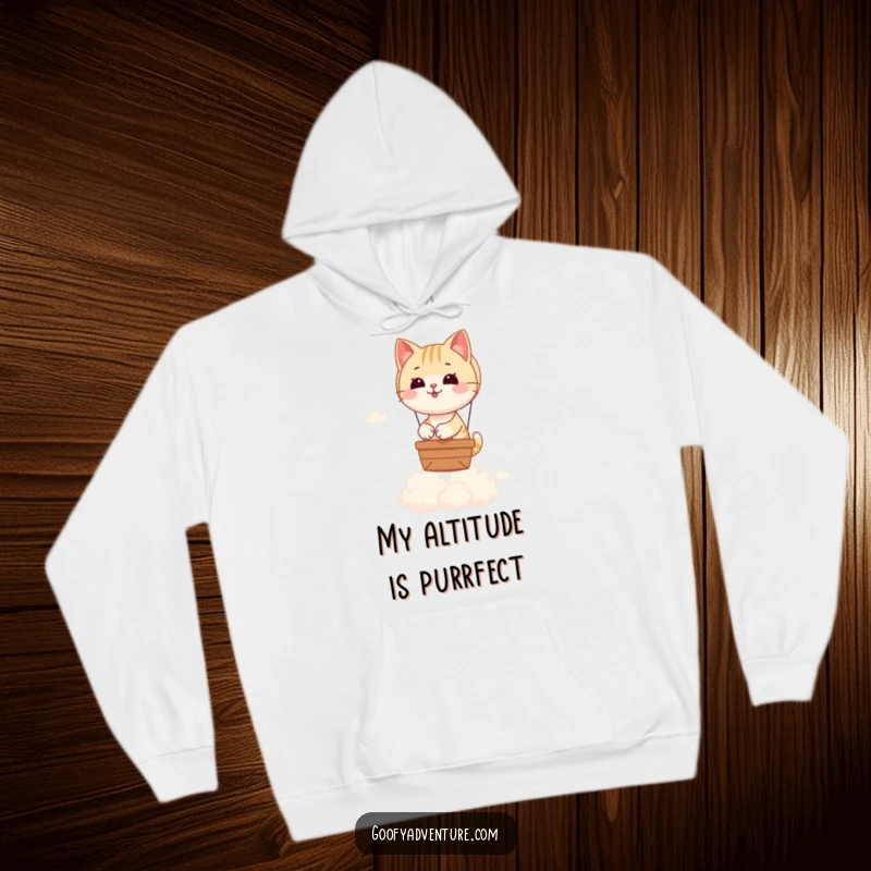 Funny hoodie depicting a playful cat steering a delightful hot air balloon high above a sea of soft, puffy clouds.